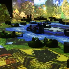 Wystawa Van Gogh w Krakowie. Widzowie odpoczywają na pufach, otoczeni projekcjami dzieł mistrza.