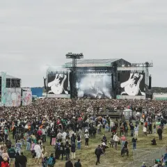 Tłum ludzi na festiwalu, wielka scena z ekranami pokazującymi gitarę. To zapewne opener 2024 lineup.