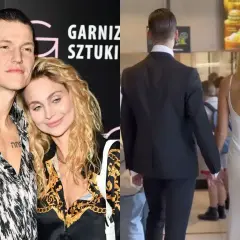 Jacek Jeschke z partnerką, w eleganckim stroju i sukni, trzymają się za ręce.