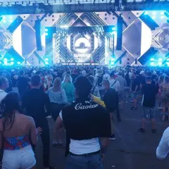 Tłum ludzi na festiwalu Sunrise w Kołobrzegu, podziwiający ogromną scenę z efektami świetlnymi.
