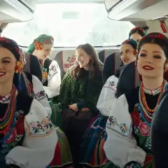 Uśmiechnięte dziewczyny w strojach ludowych, podróżujące autobusem Mazda. Kolorowe korale i haftowane bluzki.