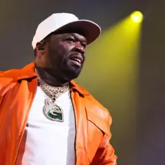 50 Cent w pomarańczowej kurtce i białej czapce, z błyszczącym naszyjnikiem. Bilety na jego koncert rozchodzą się jak ciepłe bułeczki.