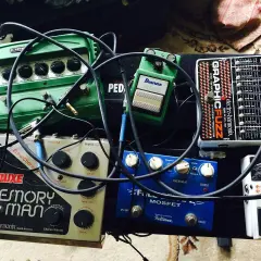 Pedalboard z efektami gitarowymi: zielony delay, srebrny Memory Man, niebieski Fulltone, czarny Electro-Harmonix i biały tuner.