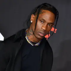 Travis Scott w czarnej koszuli i naszyjnikach na tle logo MTV.