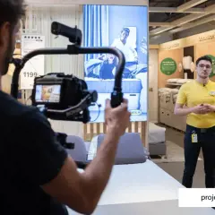 Operator kamery nagrywa pracownika IKEA w sklepie, na ekranie w tle reklama materaca.