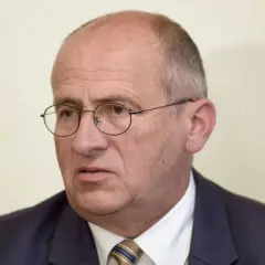 Portret starszego mężczyzny w okularach i garniturze.