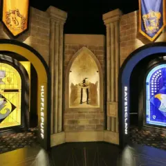 Wystawa Harry Potter: witraże Hufflepuff i Ravenclaw, a w centrum figura z kapeluszem.