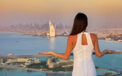 Kobieta w białej sukience podziwia panoramę Dubaju. Widok z tarasu na Burj Al Arab i Palm Jumeirah to idealne miejsce na porta party Dubai.