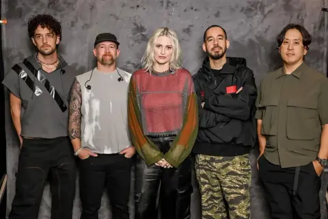Pięciu członków zespołu Linkin Park pozuje do zdjęcia na tle szarej ściany.