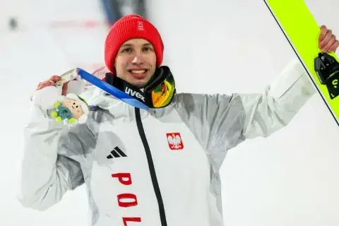 Kacper Tomasiak z medalem i nartami, dumny reprezentant Polski. Jego rodzina z pewnością cieszy się z sukcesu.