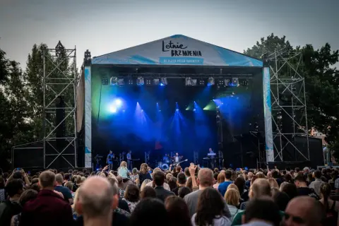 Koncert na Letnich Brzmieniach we Wrocławiu, scena z zespołem i tłum widzów.