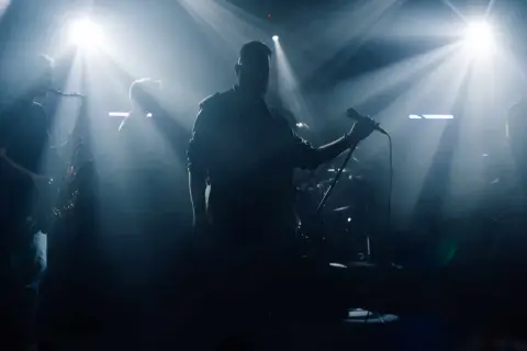 Zespół muzyczny na scenie, wokalista z mikrofonem, saksofonista, światła.