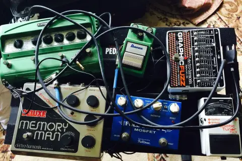 Pedalboard z efektami gitarowymi: zielony delay, srebrny Memory Man, niebieski Fulltone, czarny Electro-Harmonix i biały tuner.