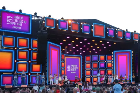 Koncert "Lato z Radiem i Telewizją Polska" w Zakopanem. Kolorowa scena z neonami i ekranami LED, artyści na scenie i tłum widzów.