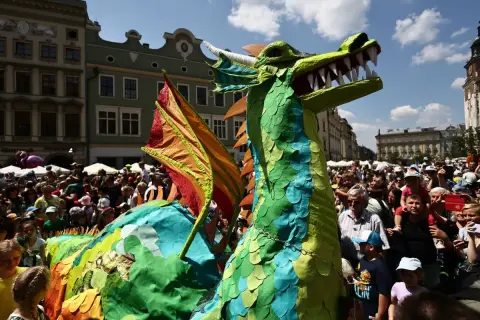 Kolorowy smok na krakowskim Rynku Głównym podczas Parady Smoków. Tłumy widzów podziwiają widowiskową postać.