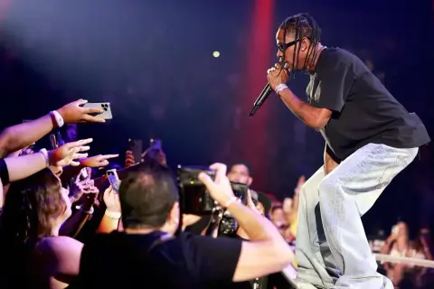 Travis Scott śpiewa na koncercie, a fani nagrywają go telefonami.
