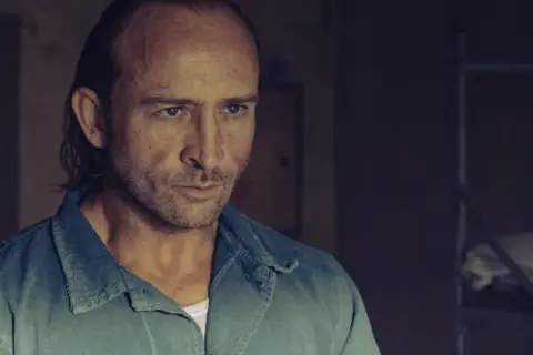 Borys Szyc w filmach często wciela się w role twardzieli. Tutaj w ponurym kadrze, zamyślony.