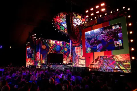 Kolorowa scena festiwalu Pol'and'Rock z wielkim ekranem wyświetlającym tłum i artystów.