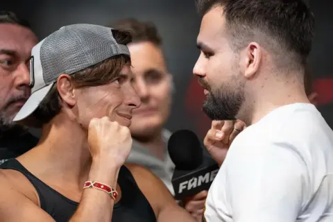 Dwóch zawodników na Fame MMA 30, jeden w czapce z daszkiem, drugi z brodą, patrzą na siebie z napięciem.
