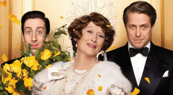 Meryl Streep w koronie i perłach, obok Hugh Granta i Simona Helberga, w scenie z jednego z jej filmów.