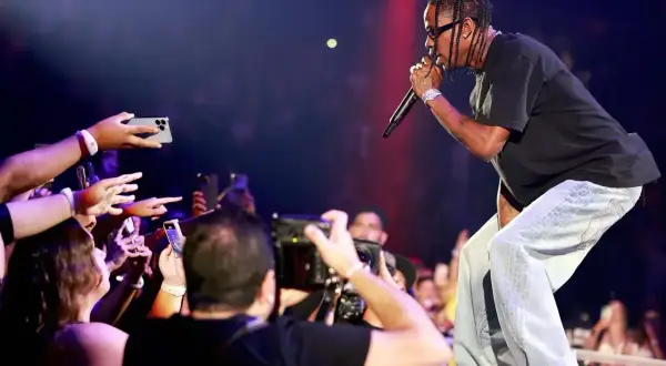 Travis Scott śpiewa na koncercie, a fani nagrywają go telefonami.