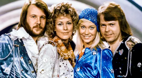 Zespół ABBA w strojach scenicznych, uśmiechnięci, patrzą w obiektyw.