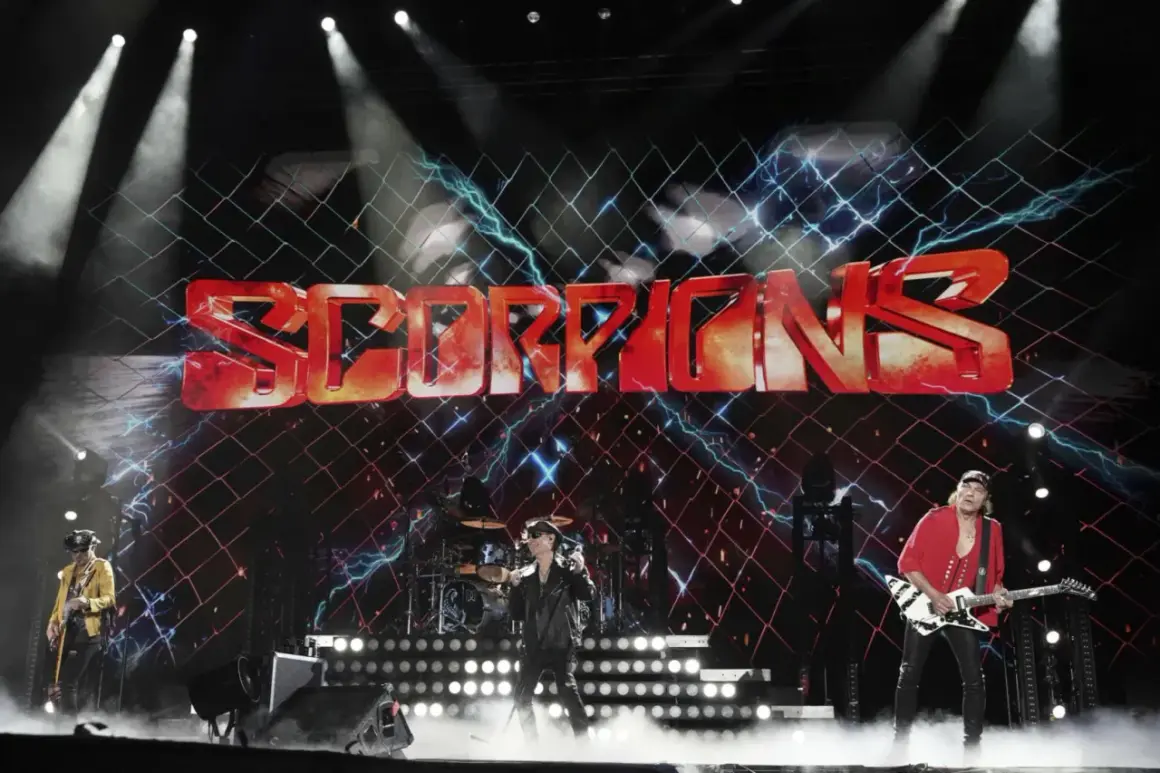 Zespół Scorpions na scenie z dużym logo zespołu i efektami świetlnymi.