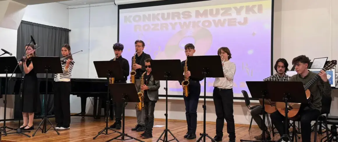 Młodzi muzycy grają na instrumentach: skrzypcach, saksofonach i gitarach, na tle ekranu z napisem "Konkurs Muzyki Rozrywkowej".