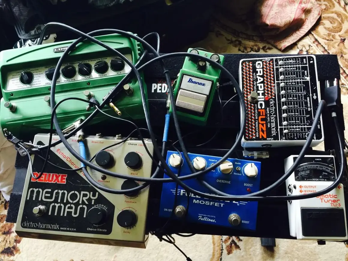 Pedalboard z efektami gitarowymi: zielony delay, srebrny Memory Man, niebieski Fulltone, czarny Electro-Harmonix i biały tuner.