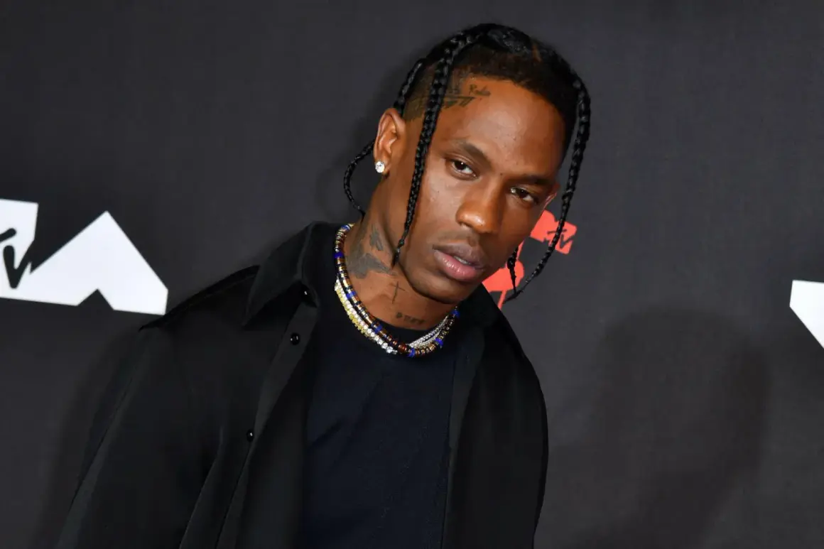 Travis Scott w czarnej koszuli i naszyjnikach na tle logo MTV.