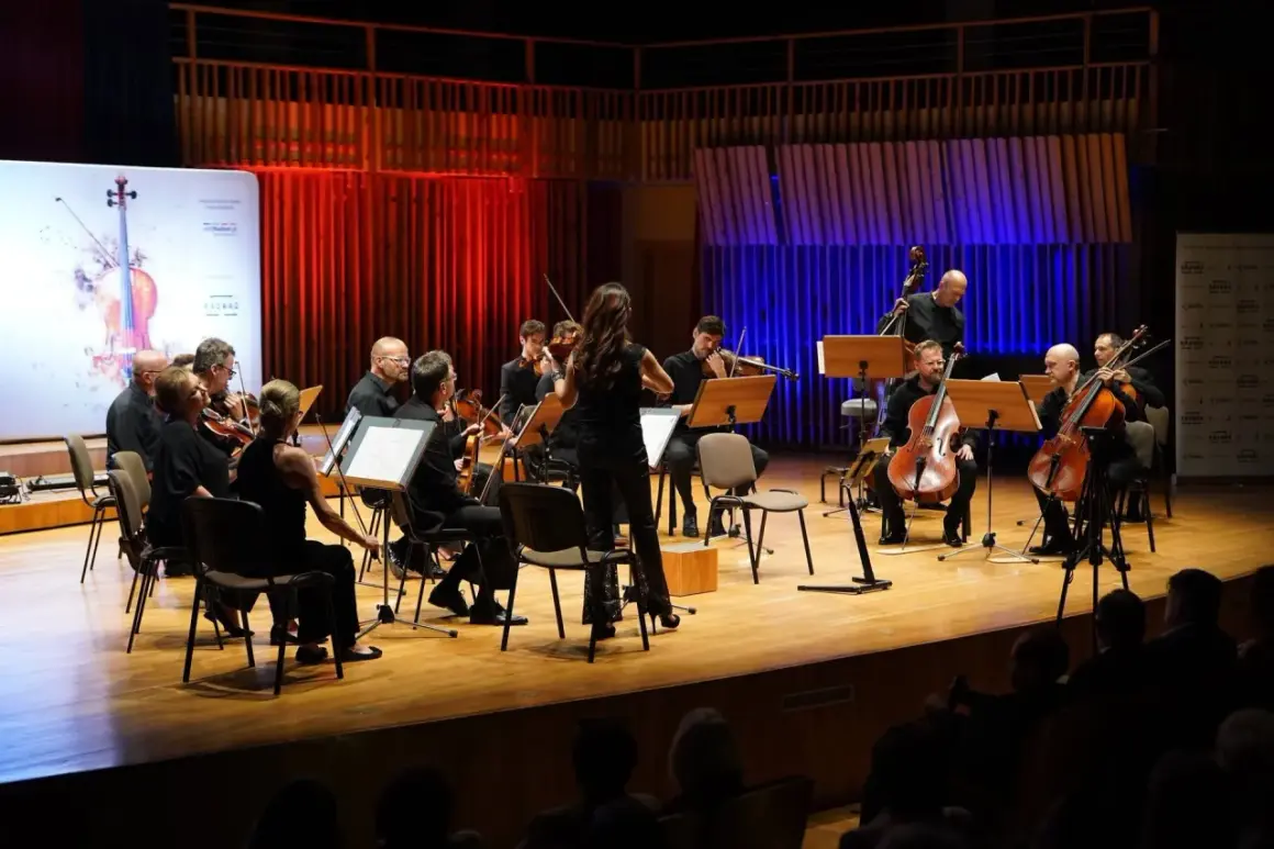 Orkiestra symfoniczna gra na scenie. W tle czerwone i niebieskie światła. Wspaniały radom koncert dzisiaj!