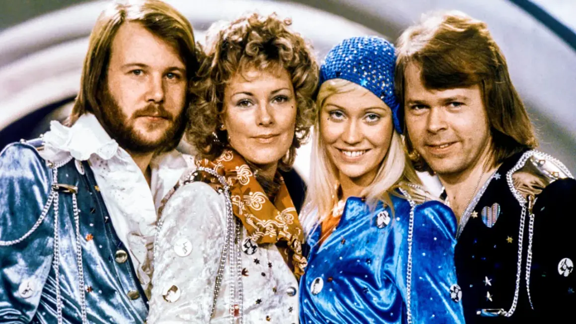 Zespół ABBA w strojach scenicznych, uśmiechnięci, patrzą w obiektyw.