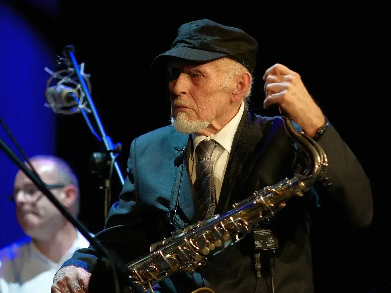 Jan Ptaszyn Wróblewski, legenda polskiego jazzu, w czapce i garniturze, z saksofonem w dłoniach.