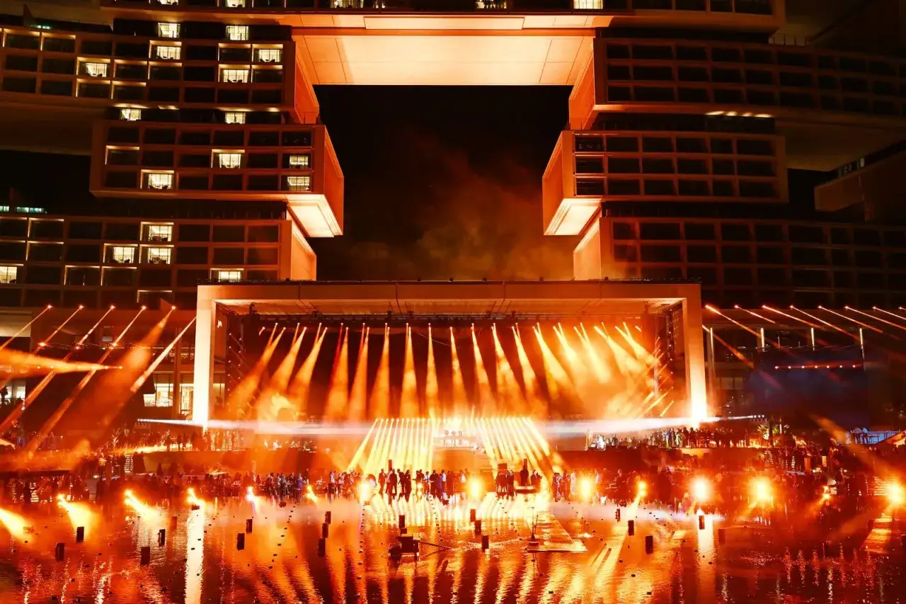 Niesamowita scena z porta party Dubai rozświetlona pomarańczowymi światłami, z tłumem ludzi i nowoczesną architekturą w tle.
