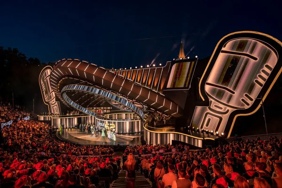 Widownia zgromadzona na koncercie festiwalowym w Opolu, podziwia scenę w kształcie gigantycznego mikrofonu.