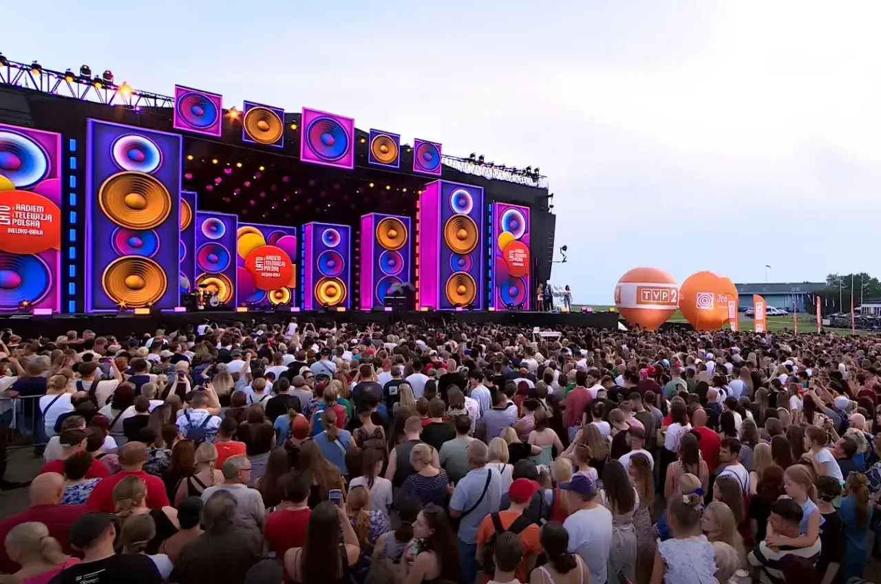 Tłumy ludzi na radom koncert dzisiaj! Wielka scena z podświetlanymi głośnikami i pomarańczowe balony w tle.