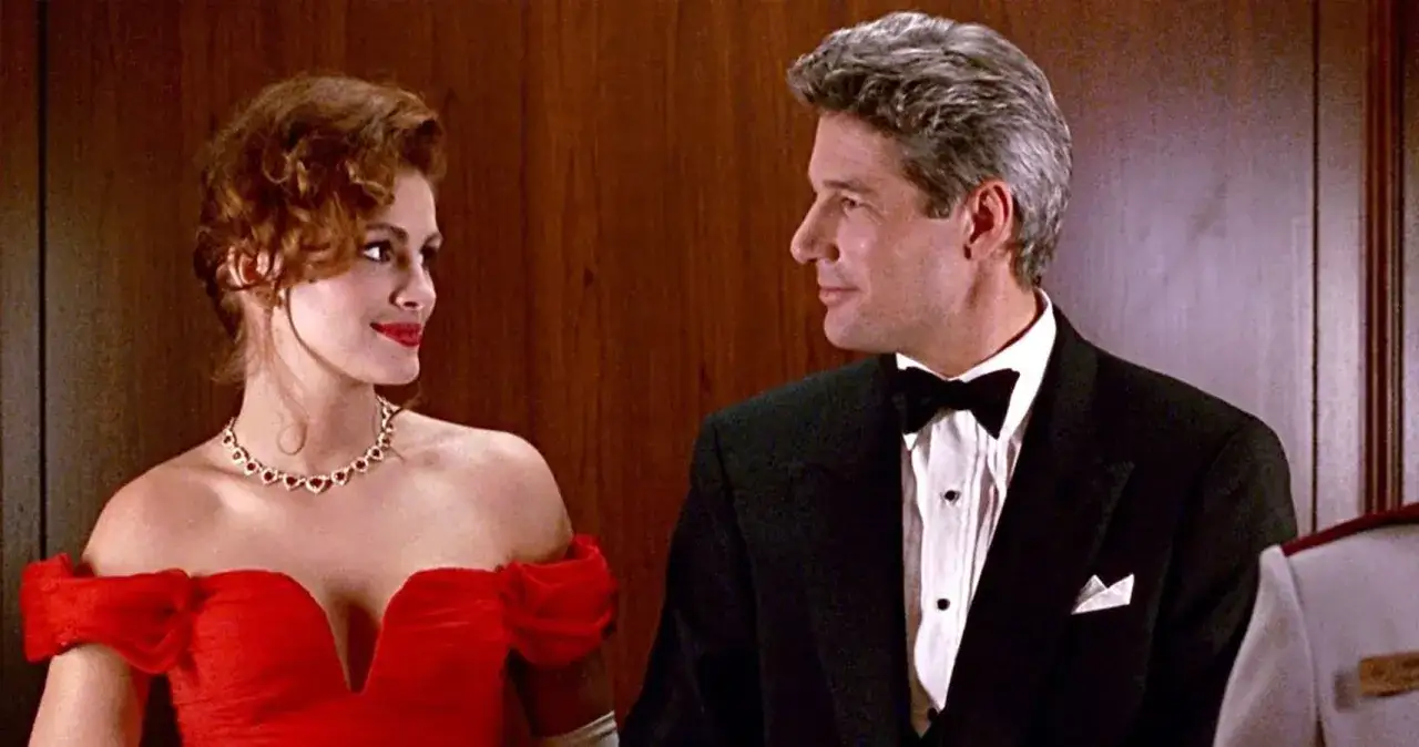 Elegancka, pretty woman w czerwonej sukni i mężczyzna w smokingu patrzą na siebie z uśmiechem.