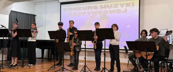 Młodzi muzycy grają na instrumentach: skrzypcach, saksofonach i gitarach, na tle ekranu z napisem "Konkurs Muzyki Rozrywkowej".