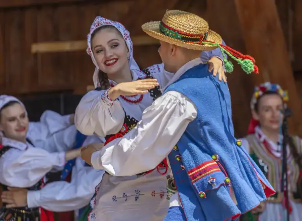 Para tańczy w tradycyjnych polskich strojach ludowych.